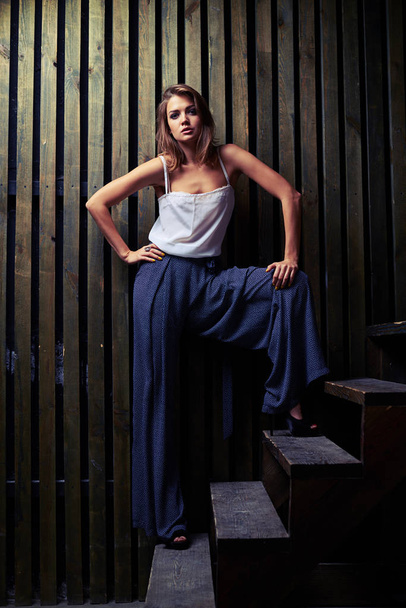 Modelo de moda moderna posando em larga posição em escadas de madeira, flo
 - Foto, Imagem
