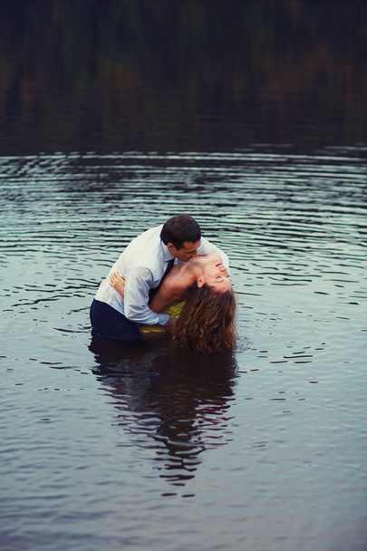 Mężczyzna całuje kobiety neck stojąc w wodzie  - Zdjęcie, obraz