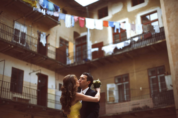 Newlyweds kiss in the front of old house with balconies  - Fotó, kép