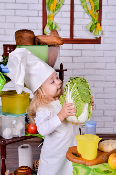 Retrato de una niña bonita en ropa de cocinero en la cocina
 - Foto, Imagen