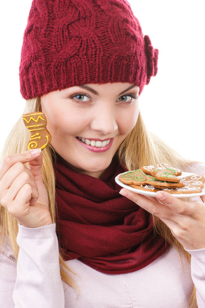 Smiling woman in woolen cap and shawl holding gingerbreads, christmas time - Photo, Image