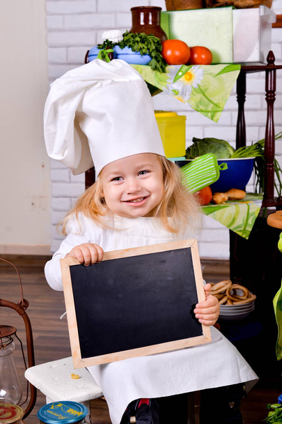 Όμορφο παιδί σεφ κρατώντας ένα πίνακα ανακοινώσεων - Φωτογραφία, εικόνα
