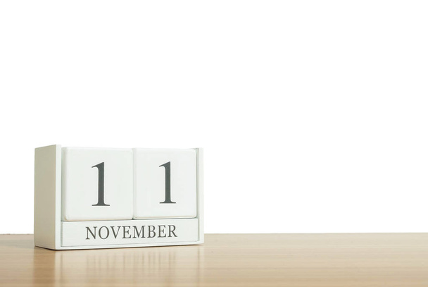 クローズ アップ表面白い木製カレンダー黒 11 月 11 日 word は、ぼやけてカレンダーをコピー スペースと白い背景、選択と集中に分離された茶色の木製の机 - 写真・画像