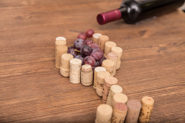 Weinflaschen, Weingläser, Trauben und Korkwein auf einem hölzernen Hintergrund. - Foto, Bild