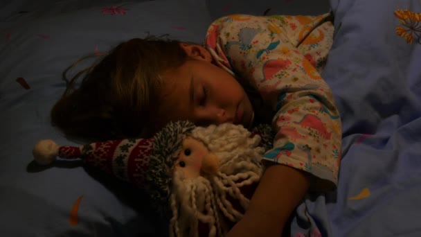 Mädchen mit Weihnachtsmann-Spielzeug schlafen in einer blauen Decke geschützt im Bett. Nahaufnahme. - Filmmaterial, Video
