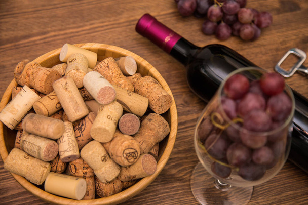 Botellas de vino, copas de vino, uvas y vino de corcho sobre un fondo de madera
. - Foto, Imagen
