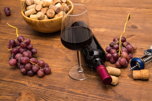 木製の背景にワインをグラスでワイン、ブドウ、コルクのワインのボトル、. - 写真・画像