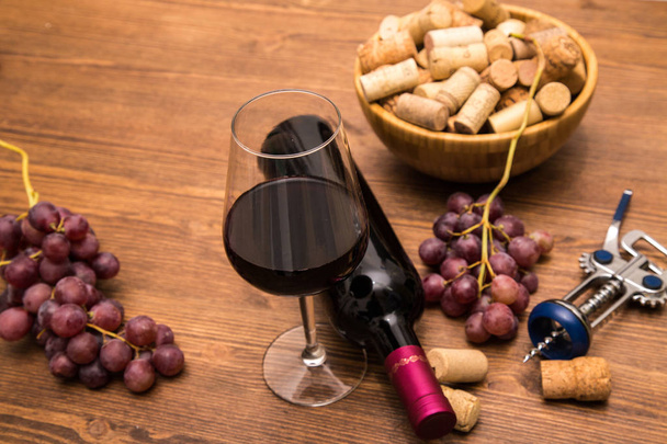 Lahve na víno, sklenice vína, vinných hroznů a vína korek na dřevěné pozadí. - Fotografie, Obrázek