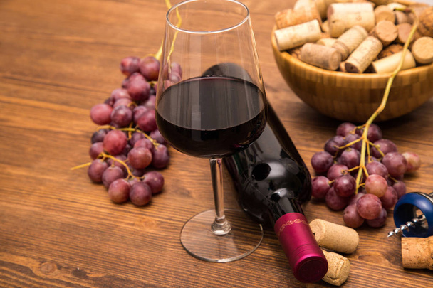 Botellas de vino, copas de vino, uvas y vino de corcho sobre un fondo de madera
. - Foto, imagen