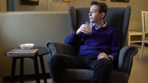 Teenager sitting in a chair and drinking coffee - Filmmaterial, Video