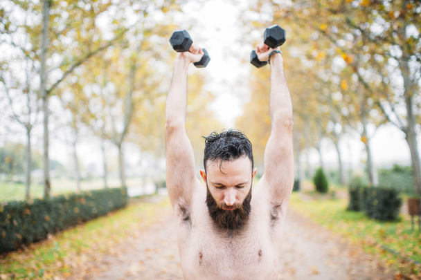 бородатый мужчина делает упражнения в парке
 - Фото, изображение