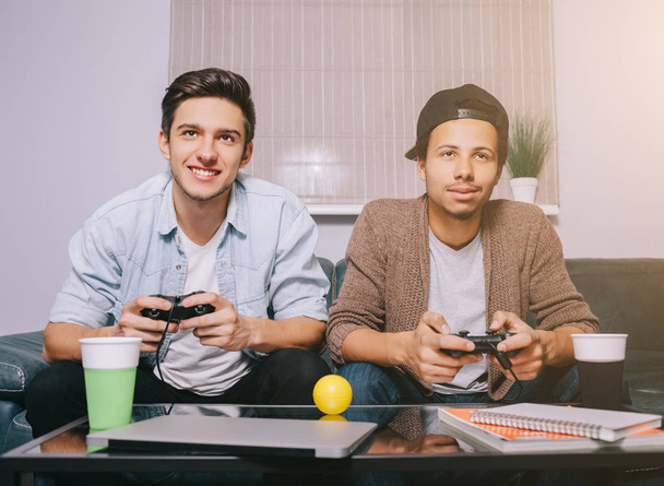 Two guys playing on the console sitting on the couch - Foto, Imagen