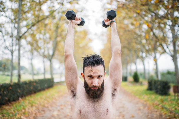 бородатый мужчина делает упражнения в парке
 - Фото, изображение