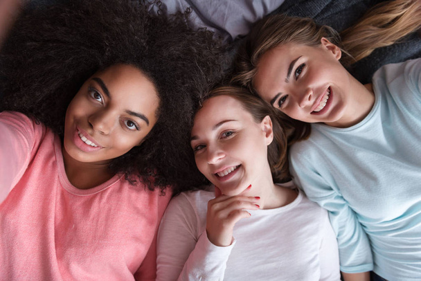 Delighted girls taking selfie lying on the bed - Photo, image