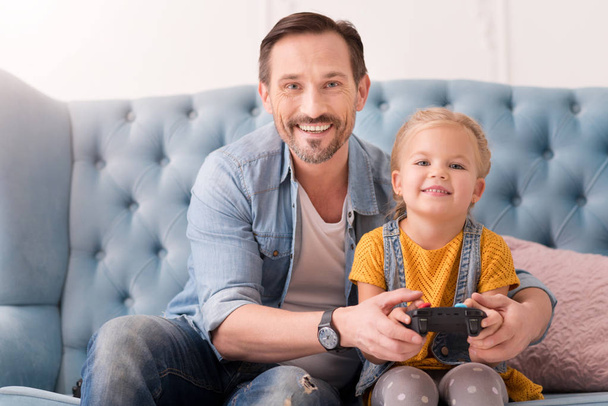 Positive caring father teaching his daughter to play video games - Photo, image