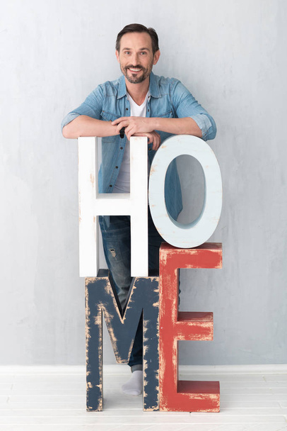 Good looking joyful man standing behind the letters HOME - Foto, Imagem