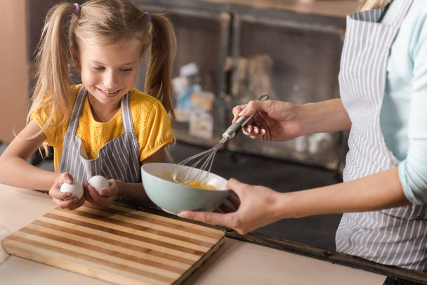 Delighted girl helping her mother in the kitchen - Foto, Imagem