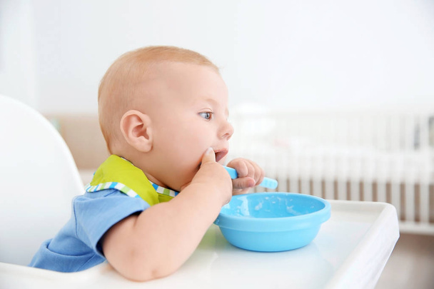 Little baby eating from bowl in kitchen - Foto, Imagem