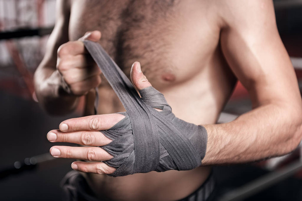 Close up of man wrapping hand in boxing tape - Foto, afbeelding