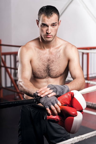 Man leaning on ring rope while holding boxing gloves - Zdjęcie, obraz