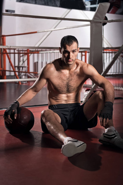Handsome sportsman sitting on floor gym - Foto, imagen
