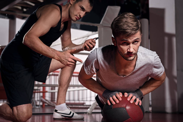 Man doing push-ups with trainer using fitness ball - Fotoğraf, Görsel