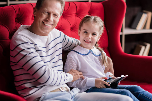 Girl resting with her grandfather and holding the game console - Fotografie, Obrázek