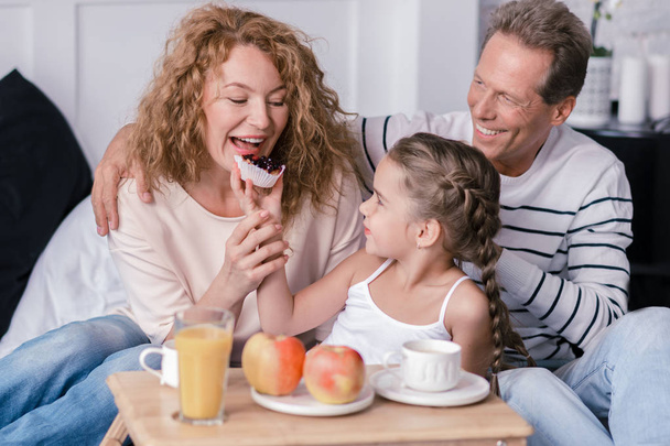 Amused girl eating berry cupcakes with her grandparents - Foto, imagen
