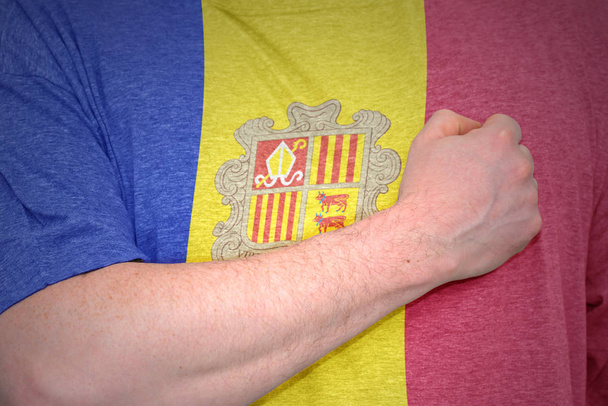 Miehen käsi t-paidassa, jossa on Andorran lippu.
. - Valokuva, kuva