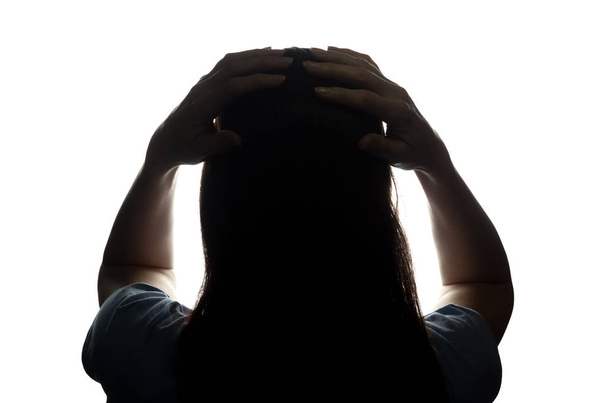 Silhouet van een jonge vrouw haar hoofd handen houden - Foto, afbeelding