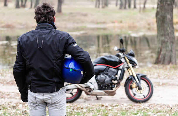 Biker stojící vedle motocyklu modrou helmu držel. - Fotografie, Obrázek