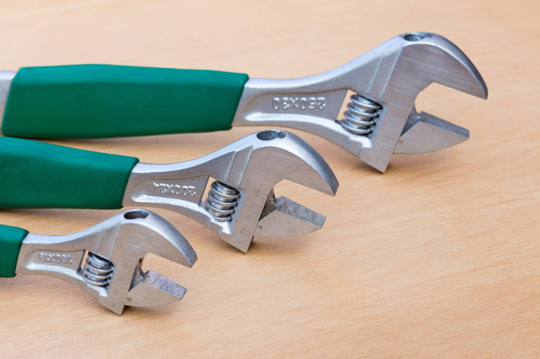 Three adjustable wrenches in row on wood - Photo, Image