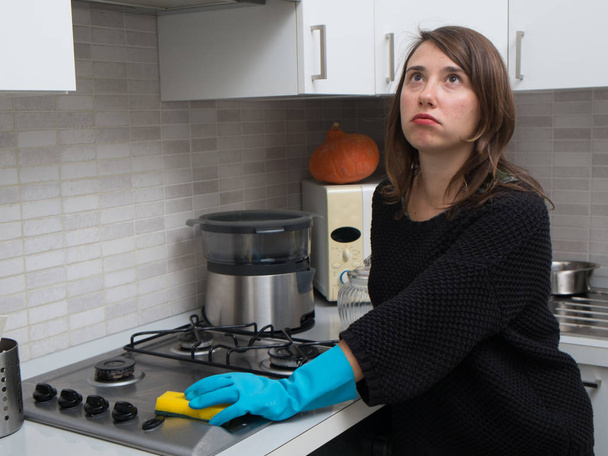 Unatkozik nő tisztítása, rozsdamentes acél gáz felület a konyhában - Fotó, kép