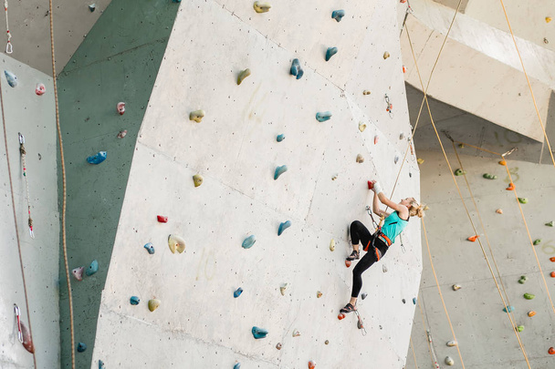 Sporty young woman exercising in a colorful climbing gym - Zdjęcie, obraz