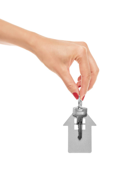 La mano sostiene la llave con un llavero la forma de la casa
. - Foto, imagen