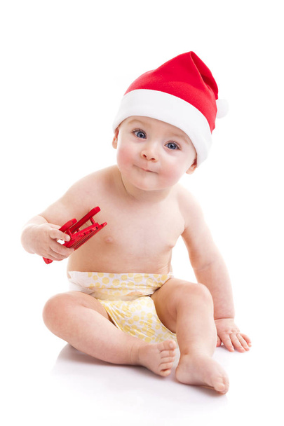 Little baby with Santa hat holding a sled - Фото, изображение