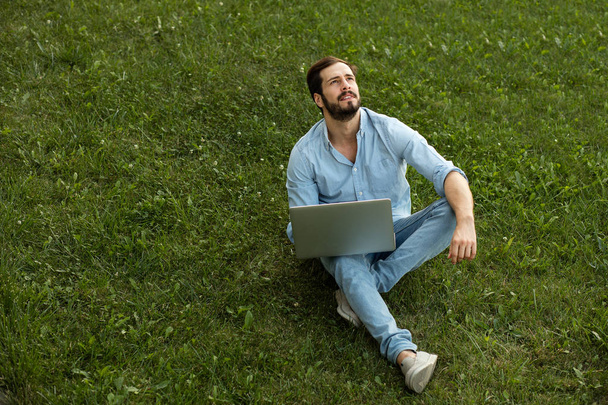 Young man in casual jeans outfit lying down with his laptop in f - Fotoğraf, Görsel