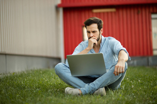 Young man in casual jeans outfit lying down with his laptop in f - Foto, immagini