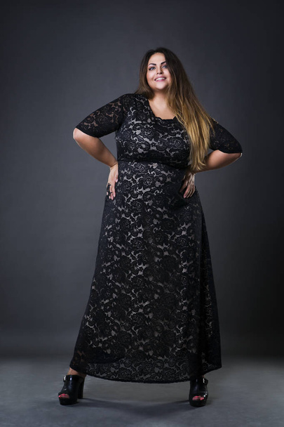 Young beautiful plus size model in black dres, xxl woman on gray studio background - Foto, afbeelding