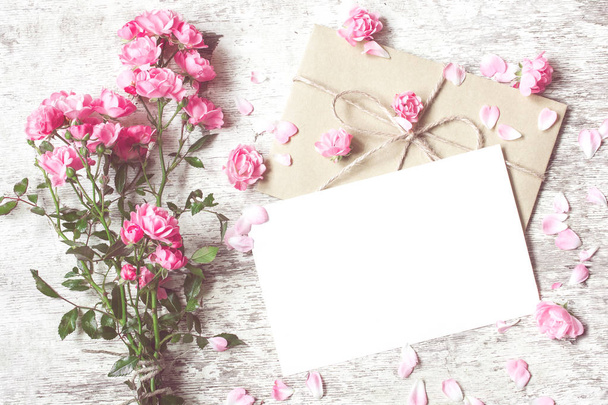 Ramo de rosas tiernas con una tarjeta de felicitación en blanco y sobre
 - Foto, imagen
