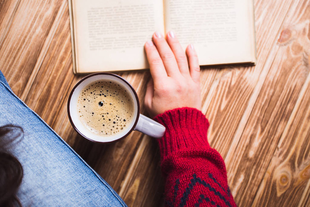 jovem mulher em uma camisola vermelha segurando uma xícara de café e leitura
 - Foto, Imagem