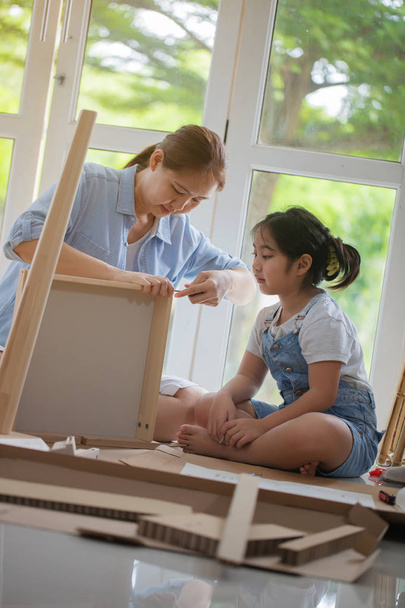 Mujer asiática enseñando a su hija a montar nuevos muebles de bricolaje en casa
 - Foto, Imagen