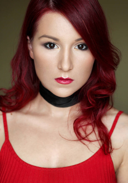Η γυναίκα νέοι κοκκινομάλλα στο κόκκινο top με μαύρη κορδέλα στο λαιμό - Φωτογραφία, εικόνα