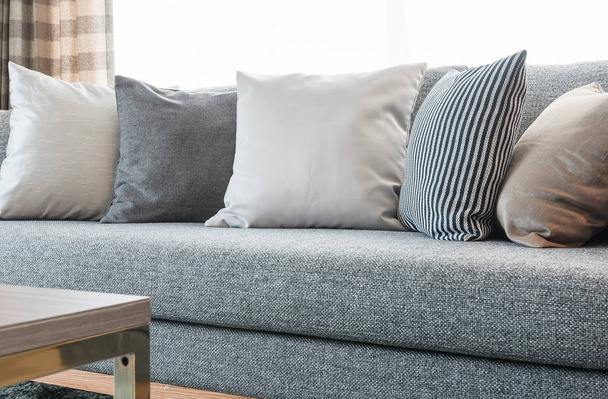 fila de almohadas en sofá gris con lámpara negra en el salón
  - Foto, imagen