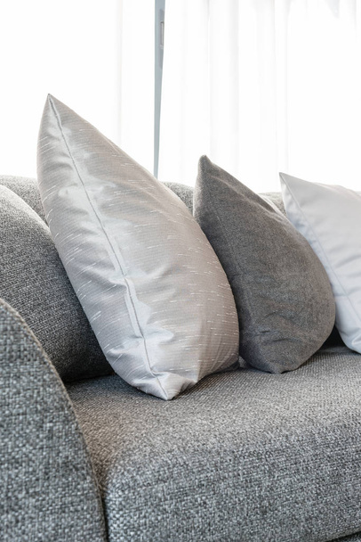 fila de almohadas en sofá gris con lámpara negra en el salón
  - Foto, imagen