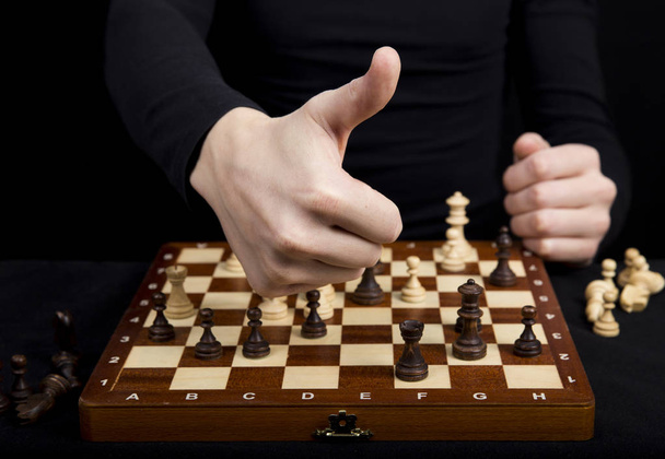 close-up de um homem segurando as mãos sobre um tabuleiro de xadrez de madeira
,  - Foto, Imagem