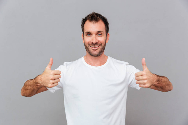 Happy casual man showing thumbs up - 写真・画像