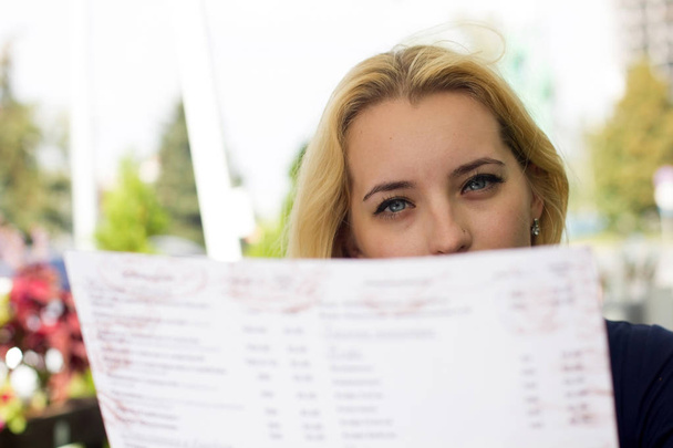blonde woman choosing from the menu - Photo, Image