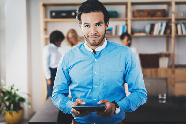 Portrait of successful confident hispanic businessman holding tablet in the hands and looking at camera in modern office.Horizontal,blurred background. - Photo, Image