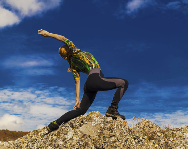 Young lady in yoga position on the rocks - Zdjęcie, obraz